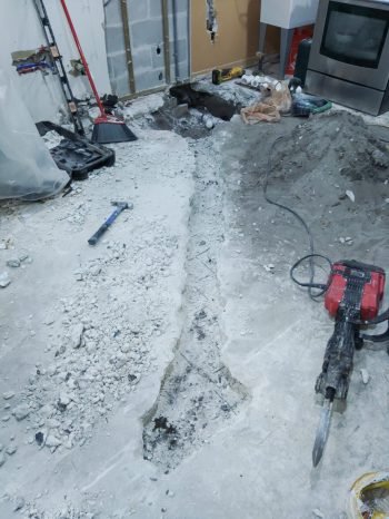 Utility trenching services in progress during floor removal and concrete cutting for utilities.